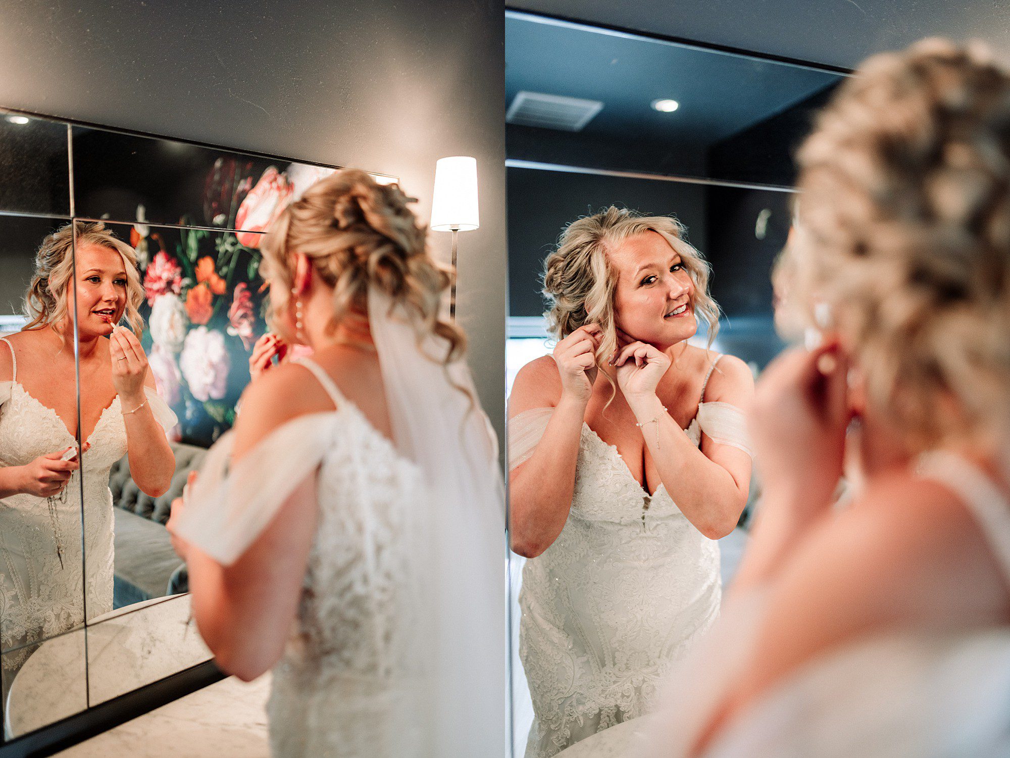 A bride in a white dress puts on earrings in front of a mirror, smiling at her reflection; the background features elegant floral wall art and soft lighting—captured beautifully by an Oshkosh WI wedding photographer at The Gibson Social Club wedding venue.