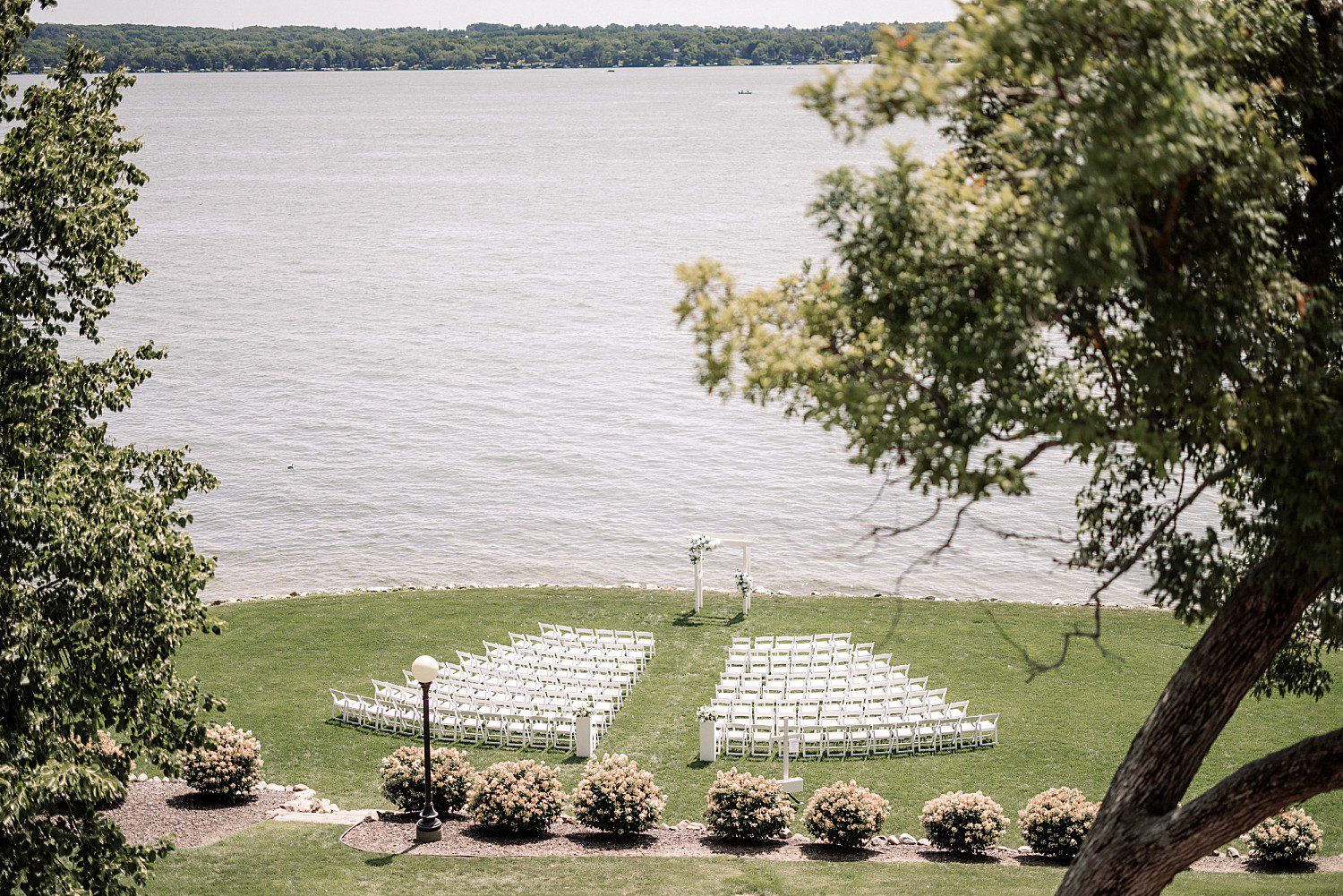 A wide view of the lakeside ceremony setup before Jenna and Josh's Heidel House wedding in Green Lake, Wisconsin