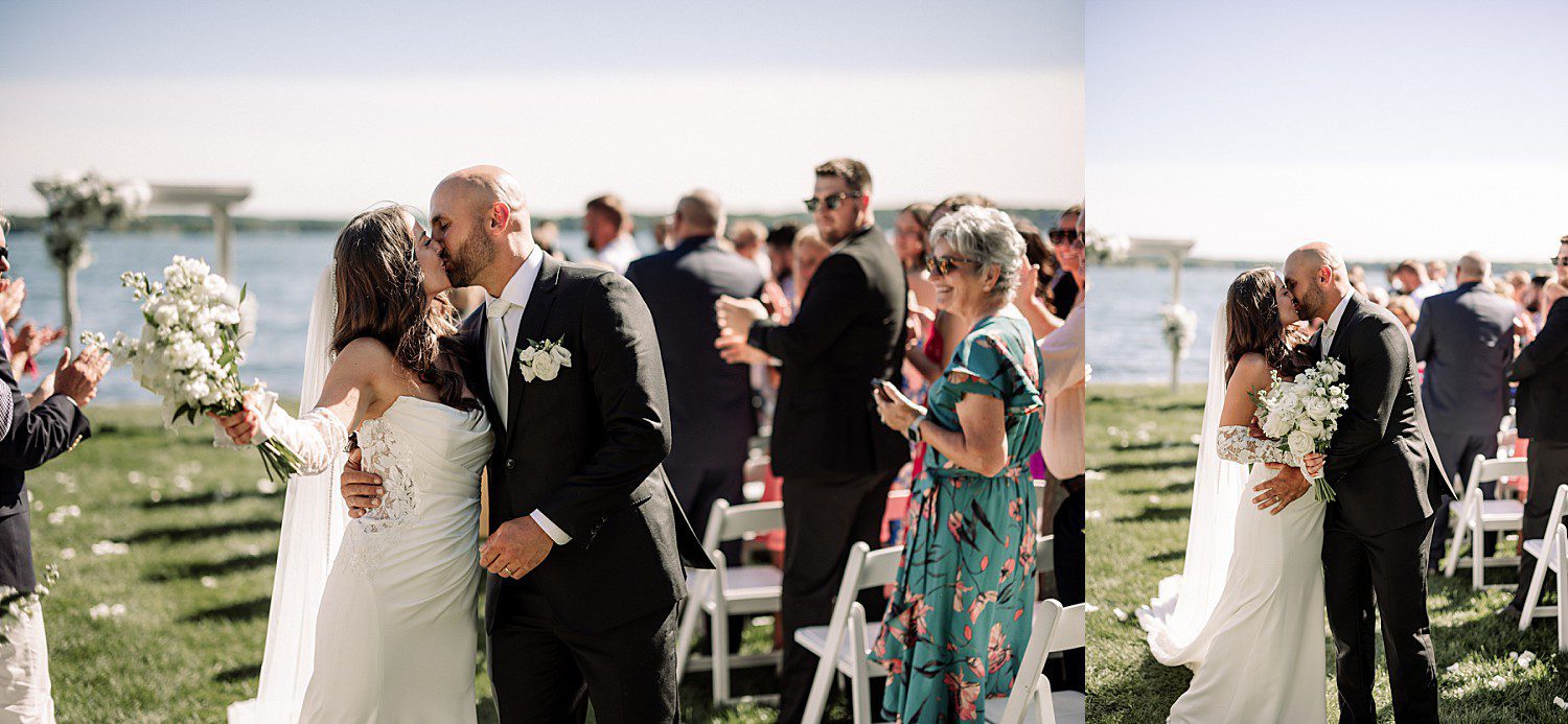 Jenna and Josh kissing as they walk back down the aisle at their Heidel House wedding, with the blooming flower cross guests built during the ceremony