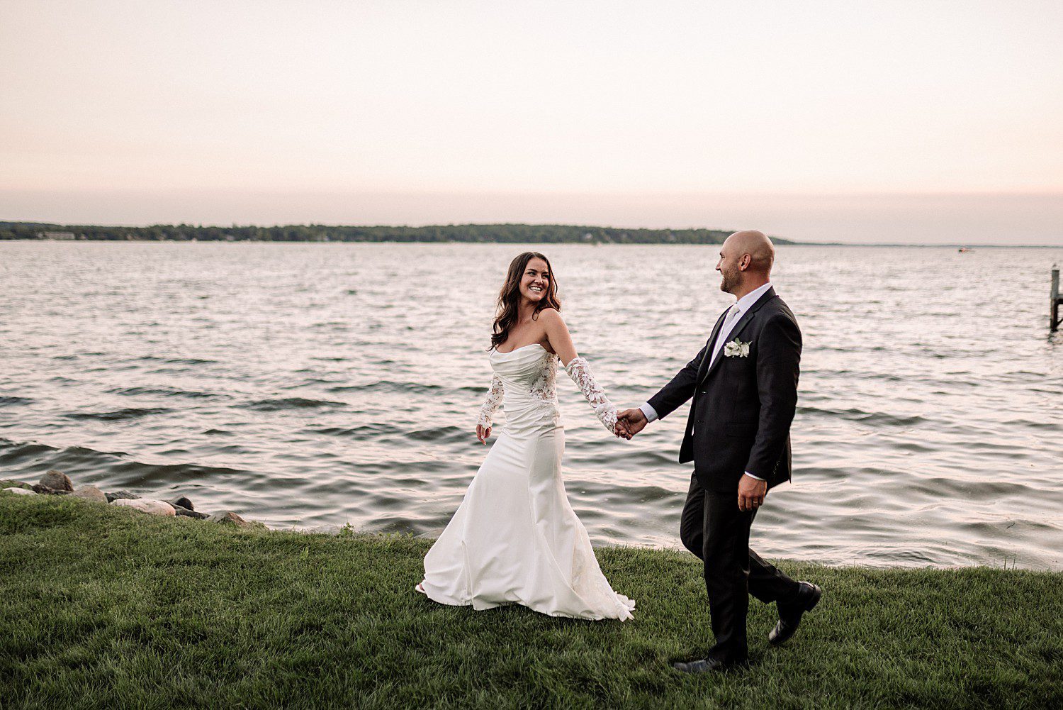 Jenna and Josh walking hand in hand along the shoreline at sunset after their Heidel House wedding
