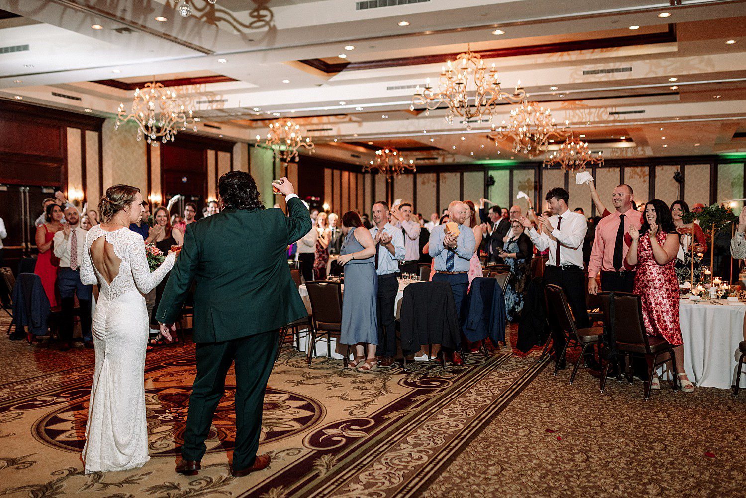 Kathryn and Logan's grand march into the ballroom as guests cheer at The Osthoff Resort in Elkhart Lake, Wisconsin