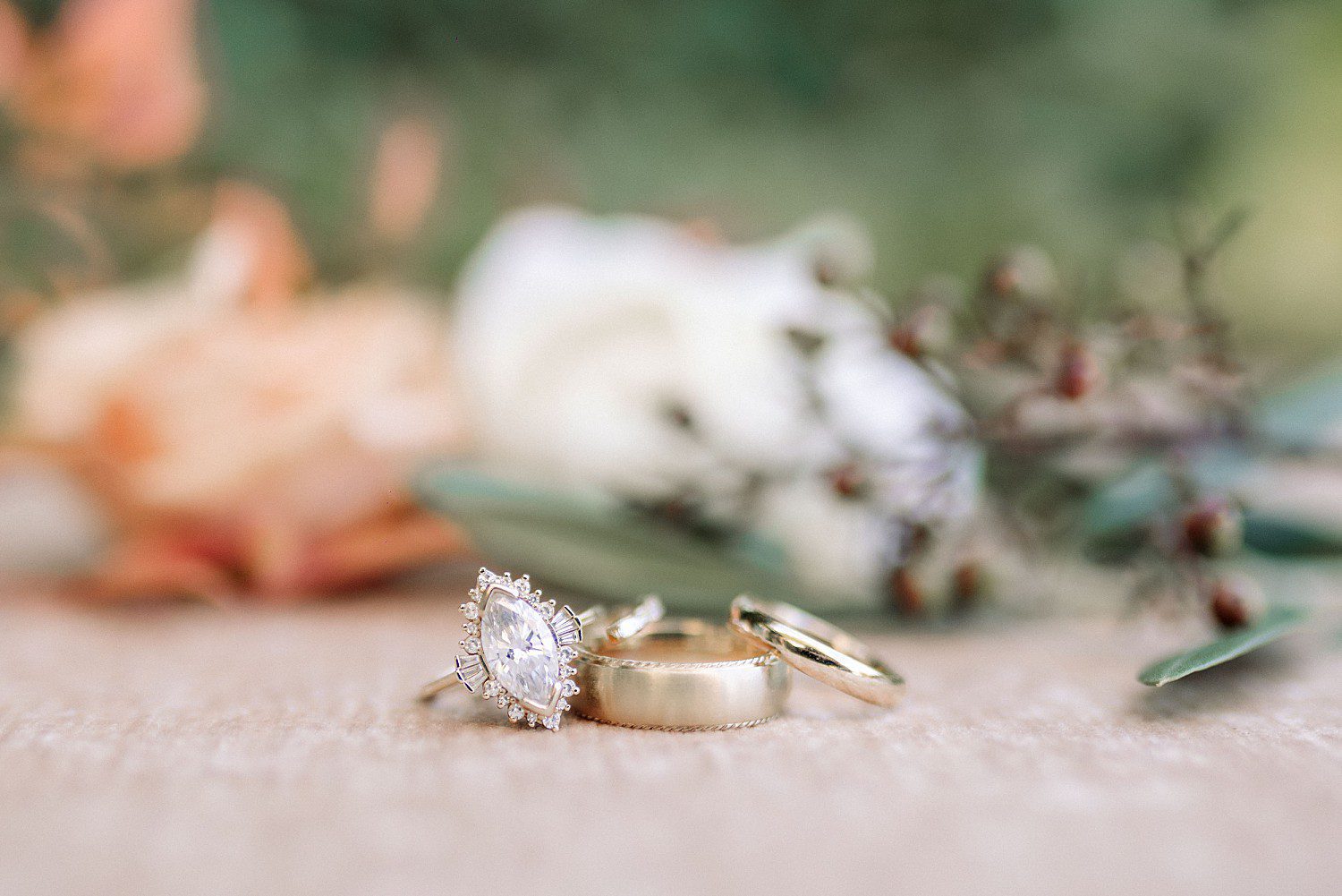 Noelle and Noah's marquise engagement ring and gold wedding bands with fall florals at Boerner Botanical Gardens in Hales Corners, Wisconsin