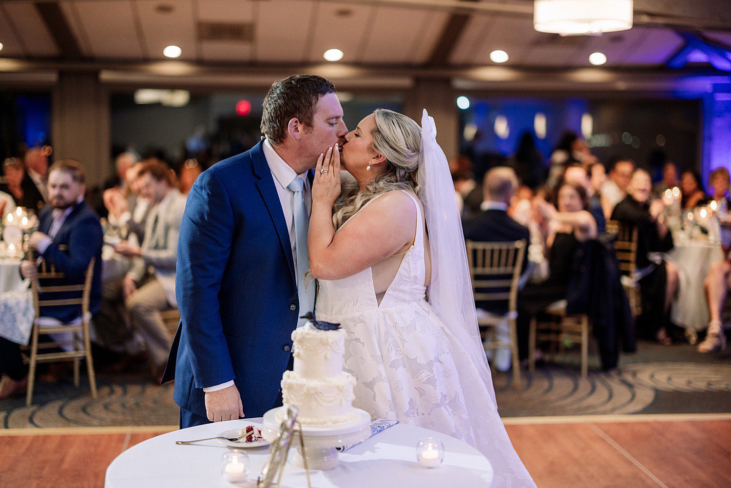 lakeside Wisconsin wedding in Delavan, Wisconsin: bride and groom kissing beside their cake table during the reception.