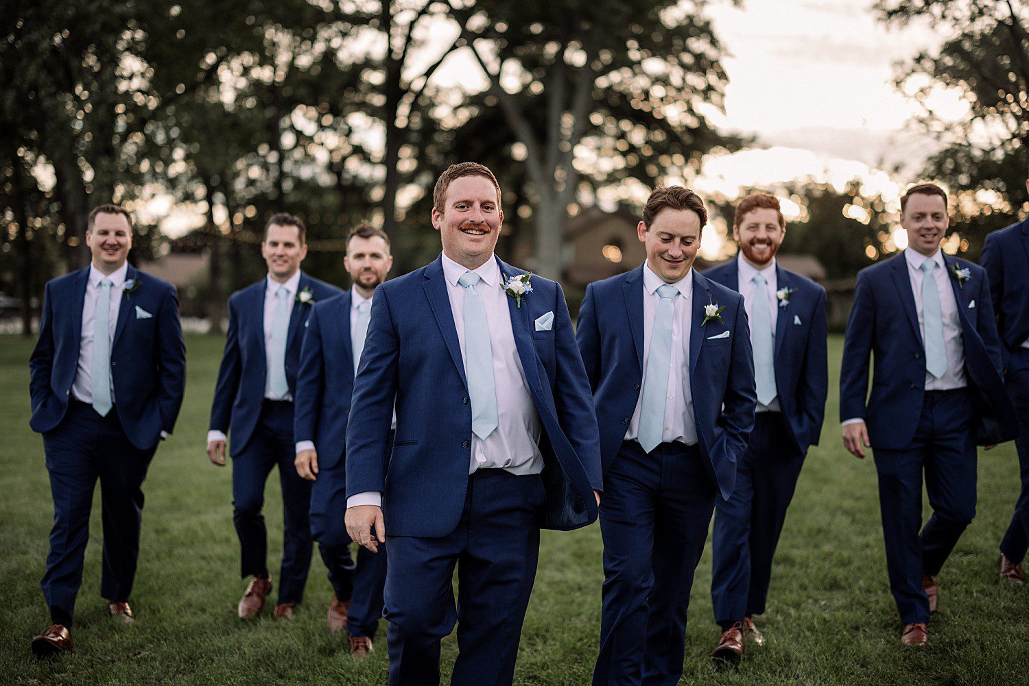 lakeside Wisconsin wedding in Delavan, Wisconsin: groom smiling in a navy suit with his groomsmen behind him.