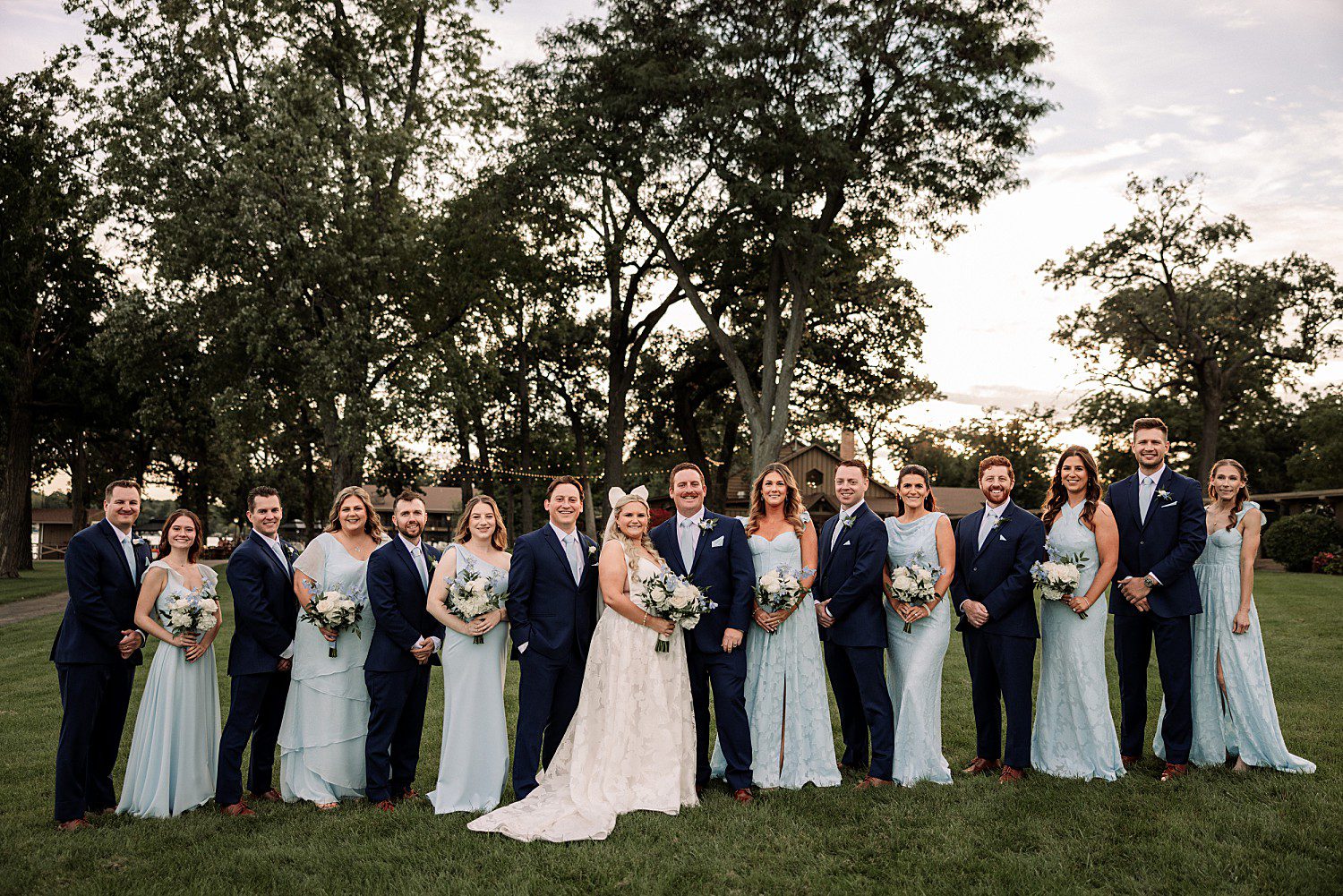 lakeside Wisconsin wedding in Delavan, Wisconsin: wedding party posing on the lawn in navy suits and pale blue dresses.